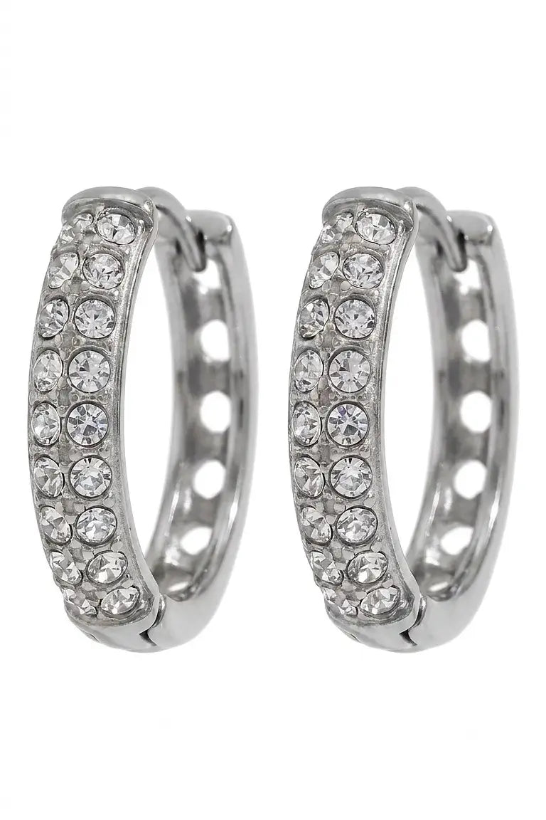 A pair of silver-toned huggie hoop earrings embellished with clear pavé gemstones, shown against a plain white background.