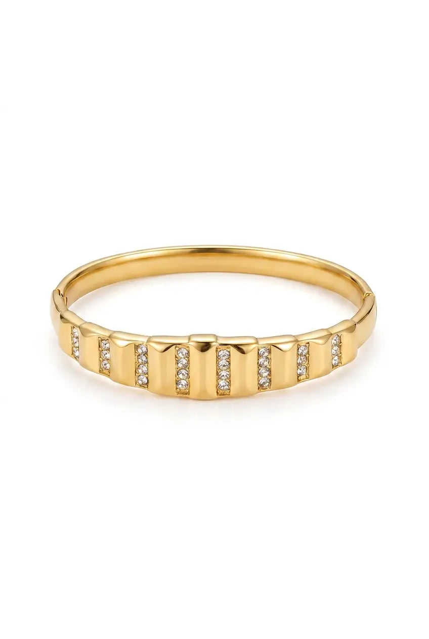 A gold bangle bracelet with a textured, segmented exterior featuring small pavé-set clear stones, shown on a plain white background.