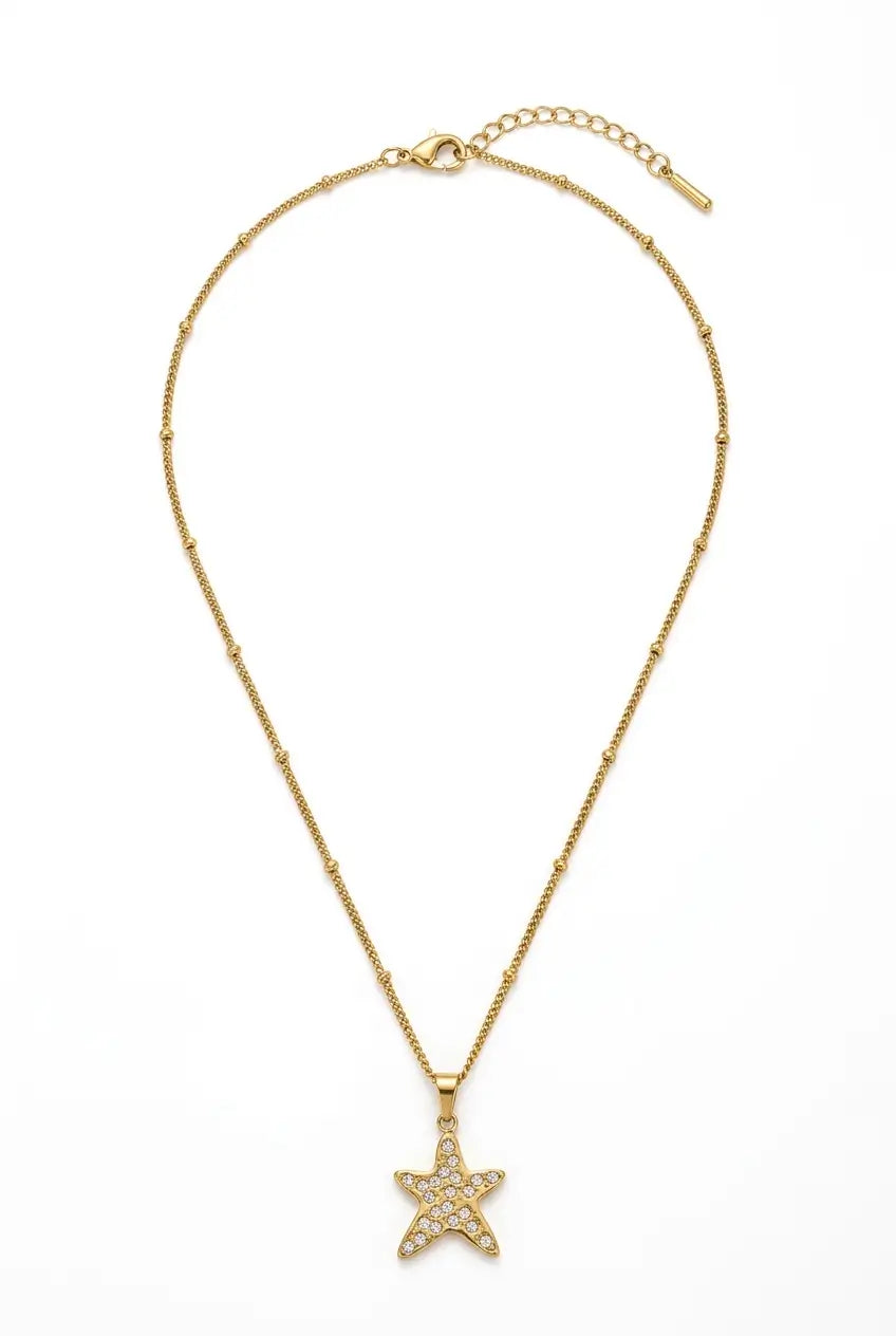 A delicate gold chain necklace featuring a small five-pointed star pendant paved with clear crystals, displayed on a clean white background.
