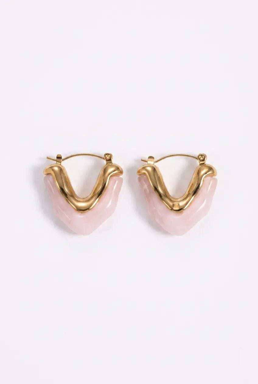 A pair of gold hoop earrings with wavy, organic-shaped pink resin inlays, displayed on a clean white background.