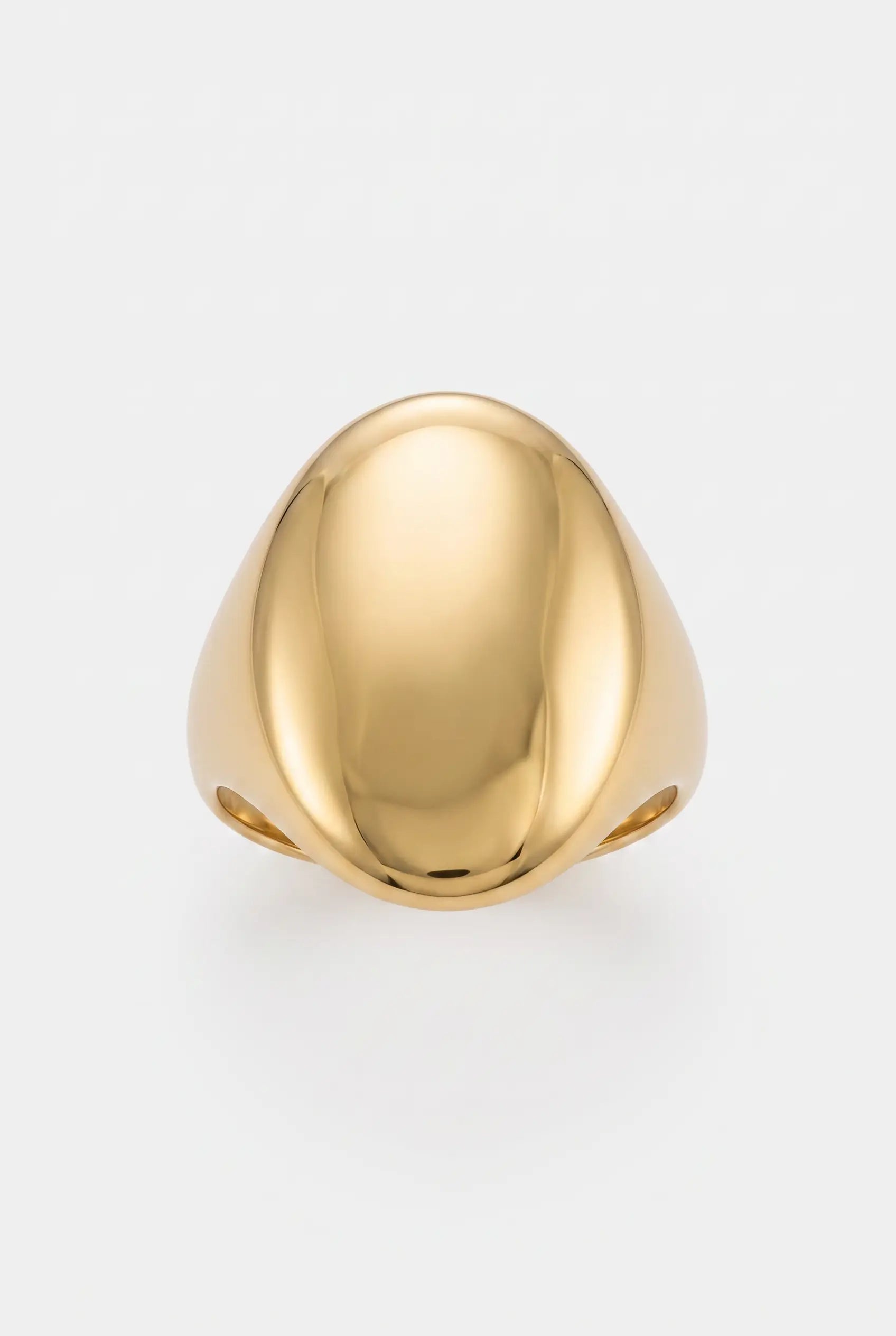 A polished gold signet ring with a smooth, rounded teardrop-shaped face, photographed on a clean, light gray background.
