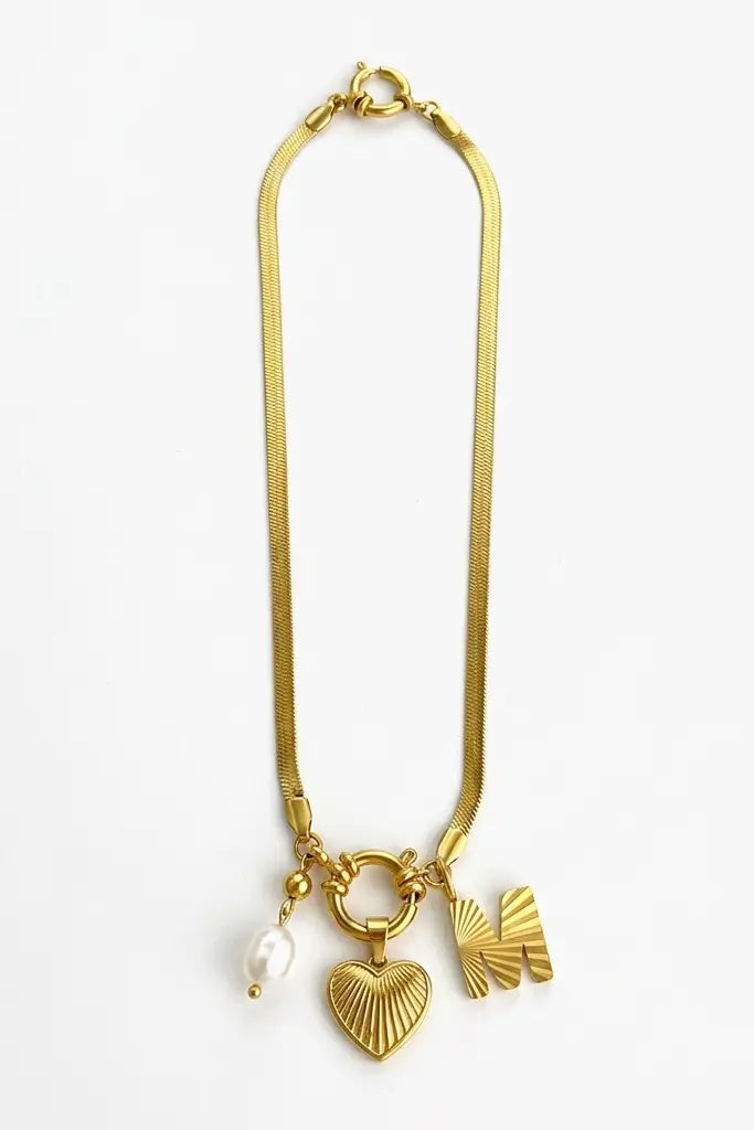 A gold-tone chain necklace with three dangling charms: a textured heart, a small fan-shaped charm, and a white pearl bead, shown on a plain white background.