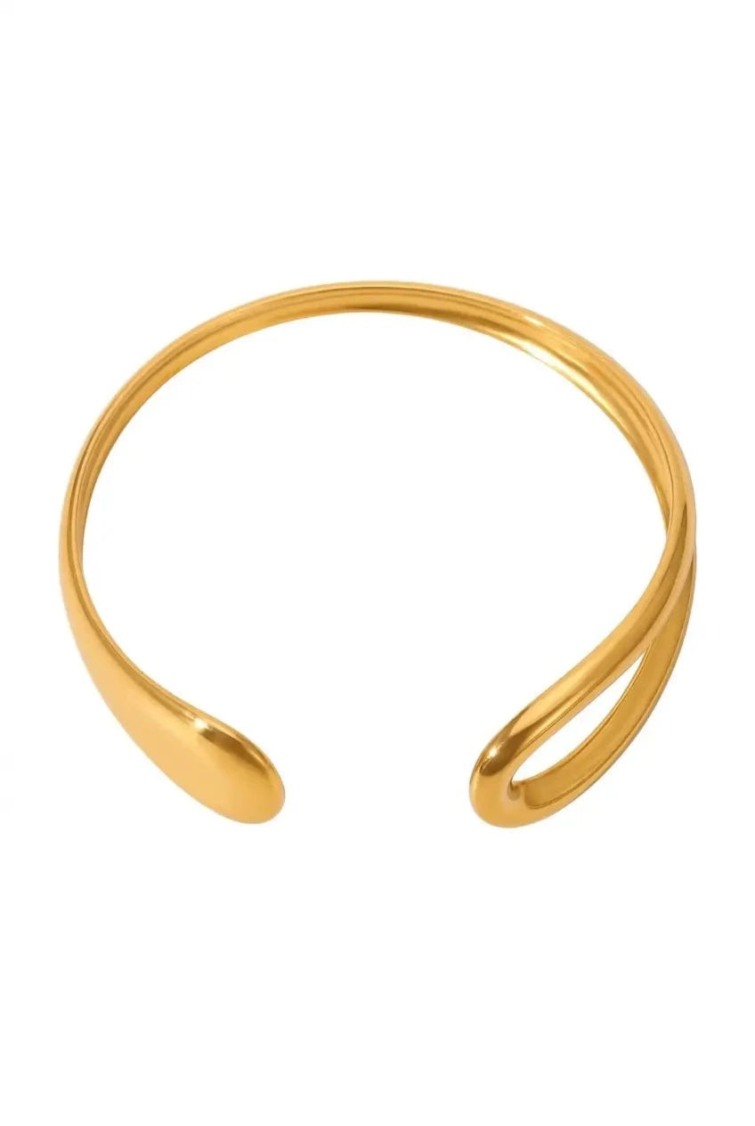 A polished gold-toned open cuff bangle with a smooth, curved organic design, shown on a plain white background.