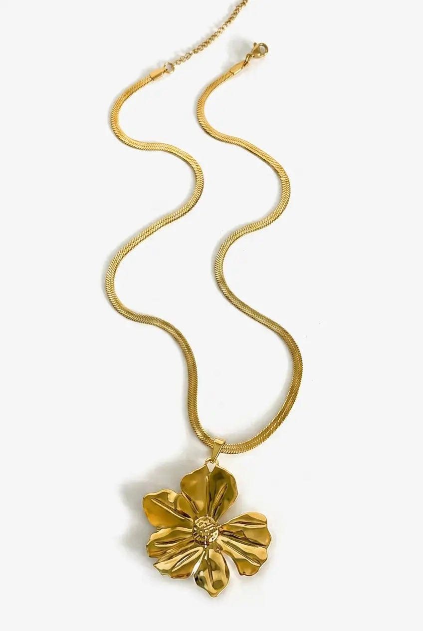 A gold snake chain necklace featuring a textured, sculptural flower pendant, displayed against a clean white background.