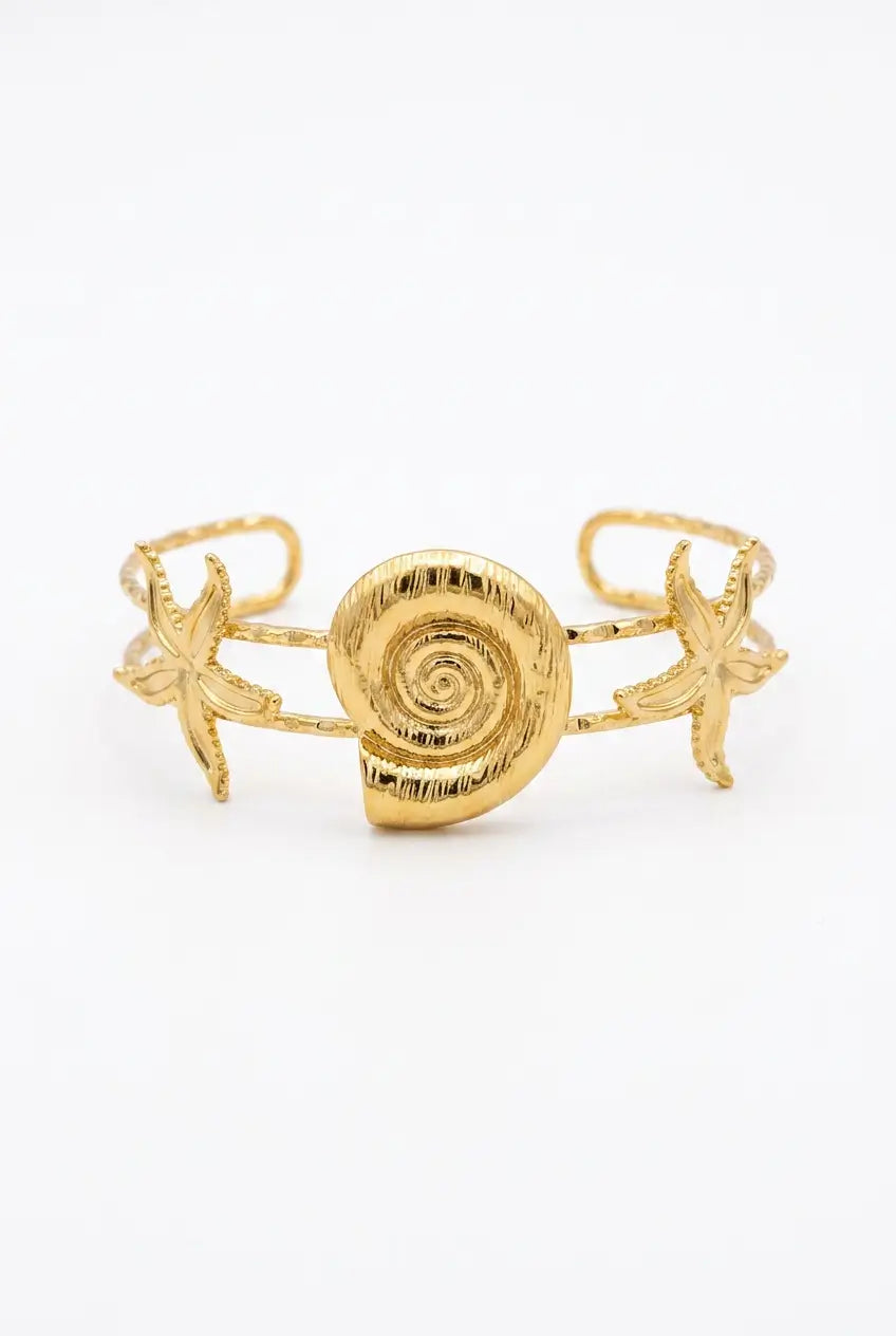 A gold-toned open cuff bracelet featuring a central spiral shell motif flanked by two starfish details, shown on a plain white background.