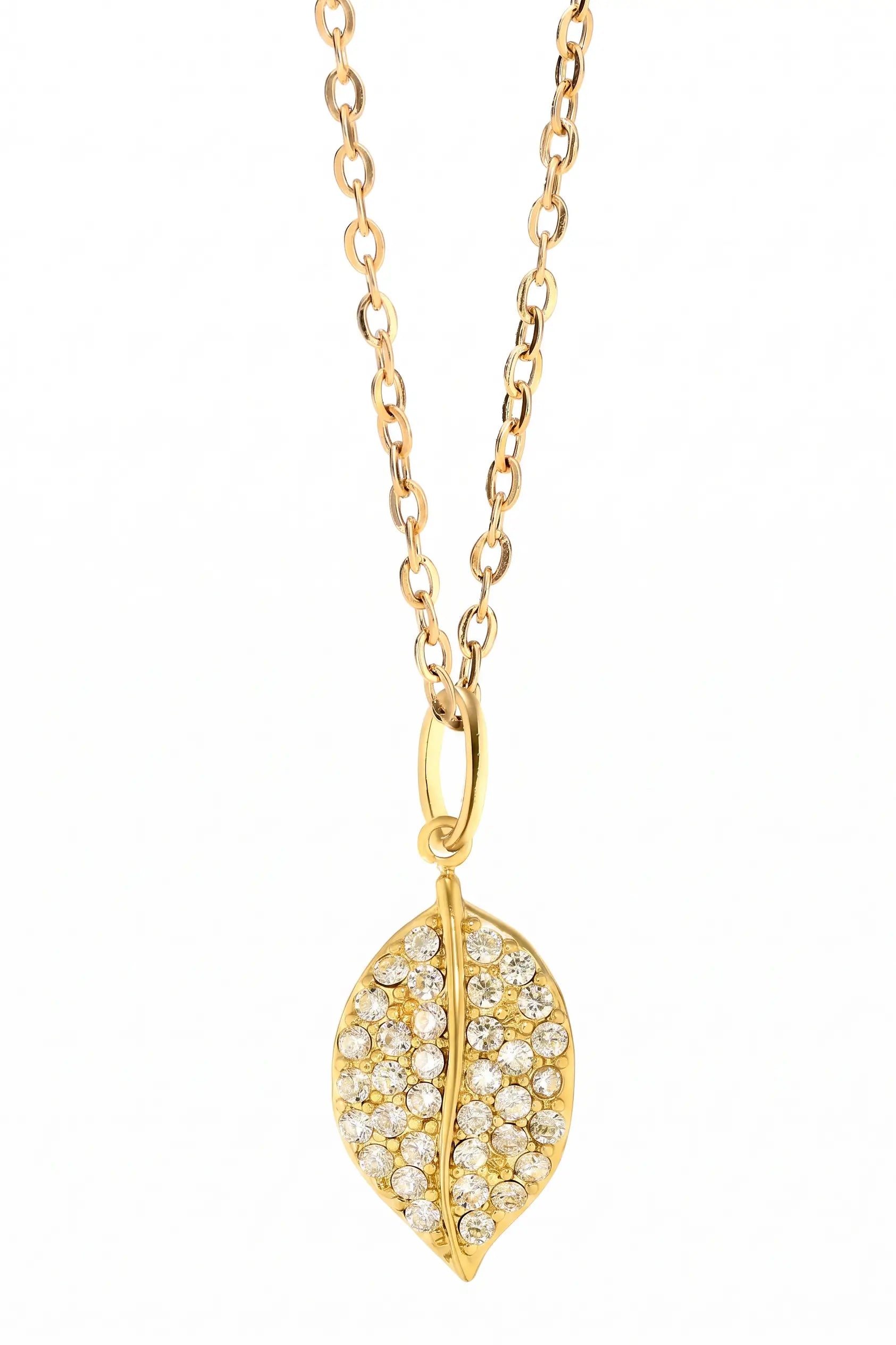 A gold leaf pendant necklace paved with small clear stones, shown against a plain white background.