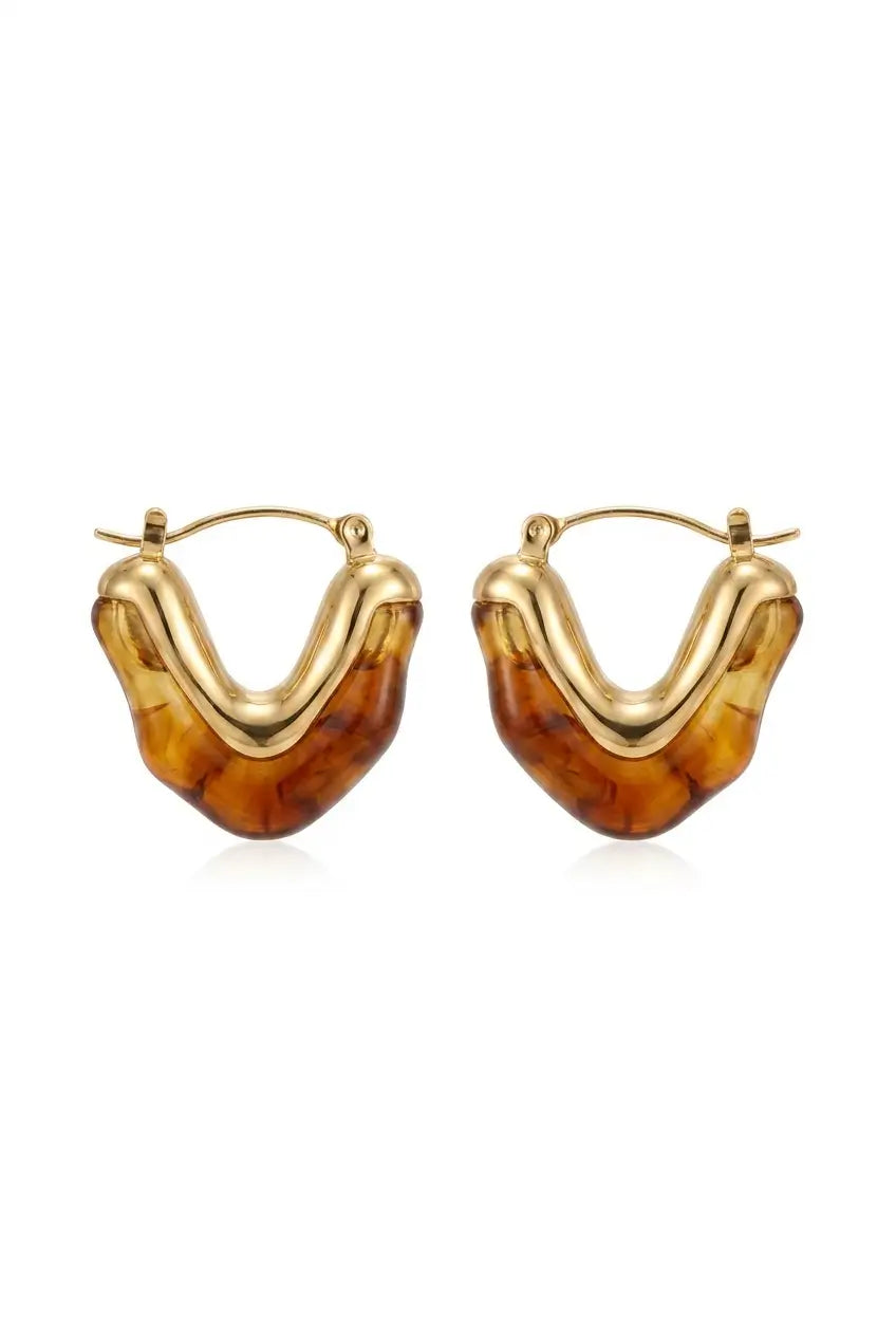 A pair of gold hoop earrings with organic, wavy U-shaped amber resin inserts, shown on a plain white background.