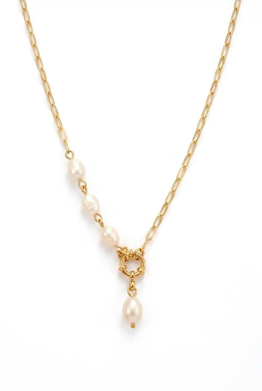 A gold chain necklace featuring a series of small white freshwater pearls leading to a decorative gold clasp with a dangling pearl, shown on a plain white background.