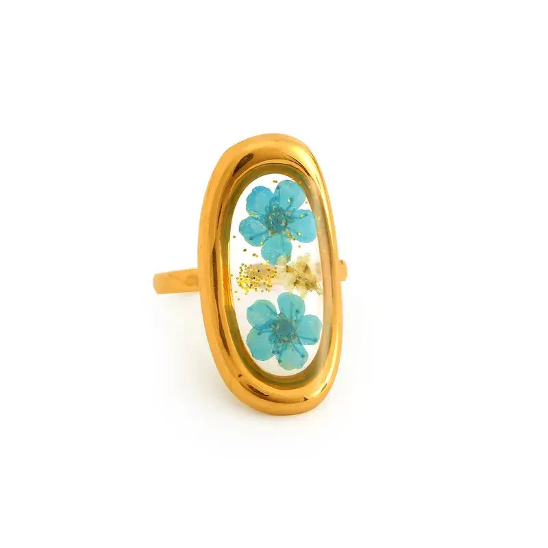 Gold ring with oval design featuring blue flowers on a white background