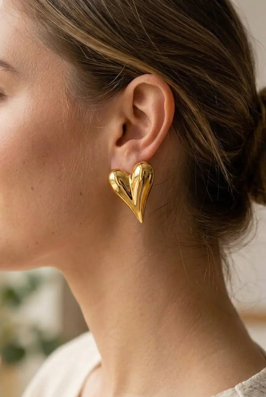 A close-up side profile of a woman wearing a shiny gold heart-shaped dangle earring.