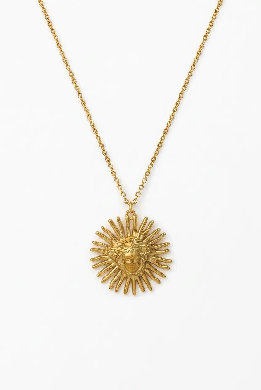 A gold-tone chain necklace featuring a sunburst pendant with a central lion head motif, displayed against a clean white background.