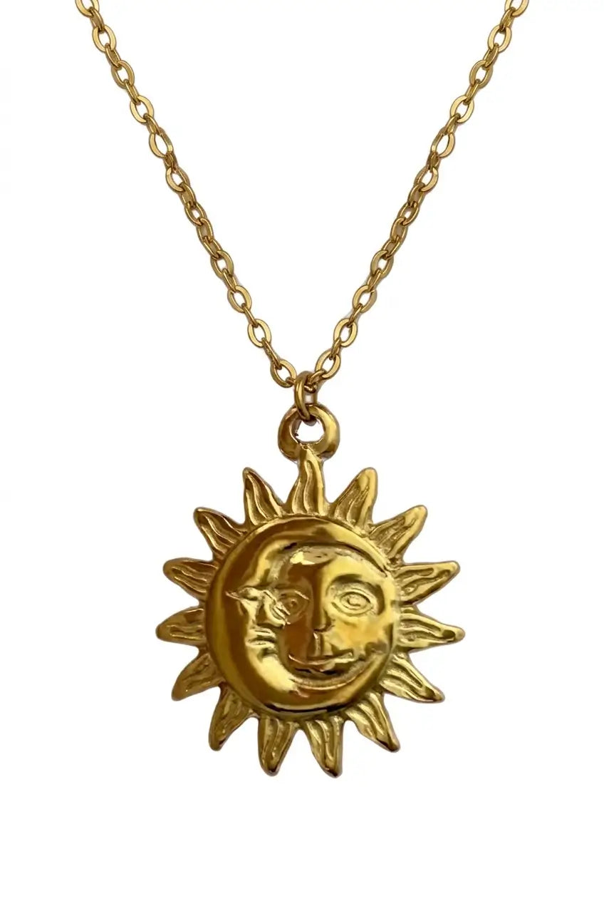 A gold-toned necklace featuring a sun and moon pendant with a stylized human face, shown against a plain white background.