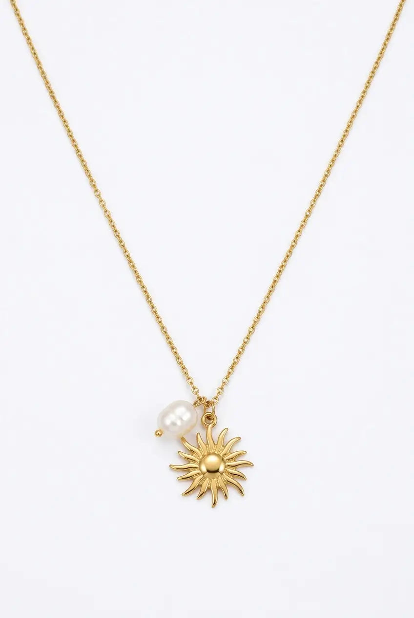 A delicate gold chain necklace featuring a small gold sun pendant and a small white pearl bead, displayed against a clean white background.