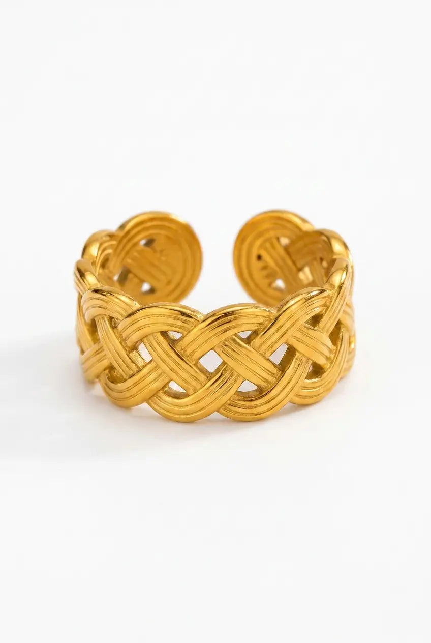 A gold-toned open cuff ring with an intricate braided interlaced pattern, photographed on a clean white background.