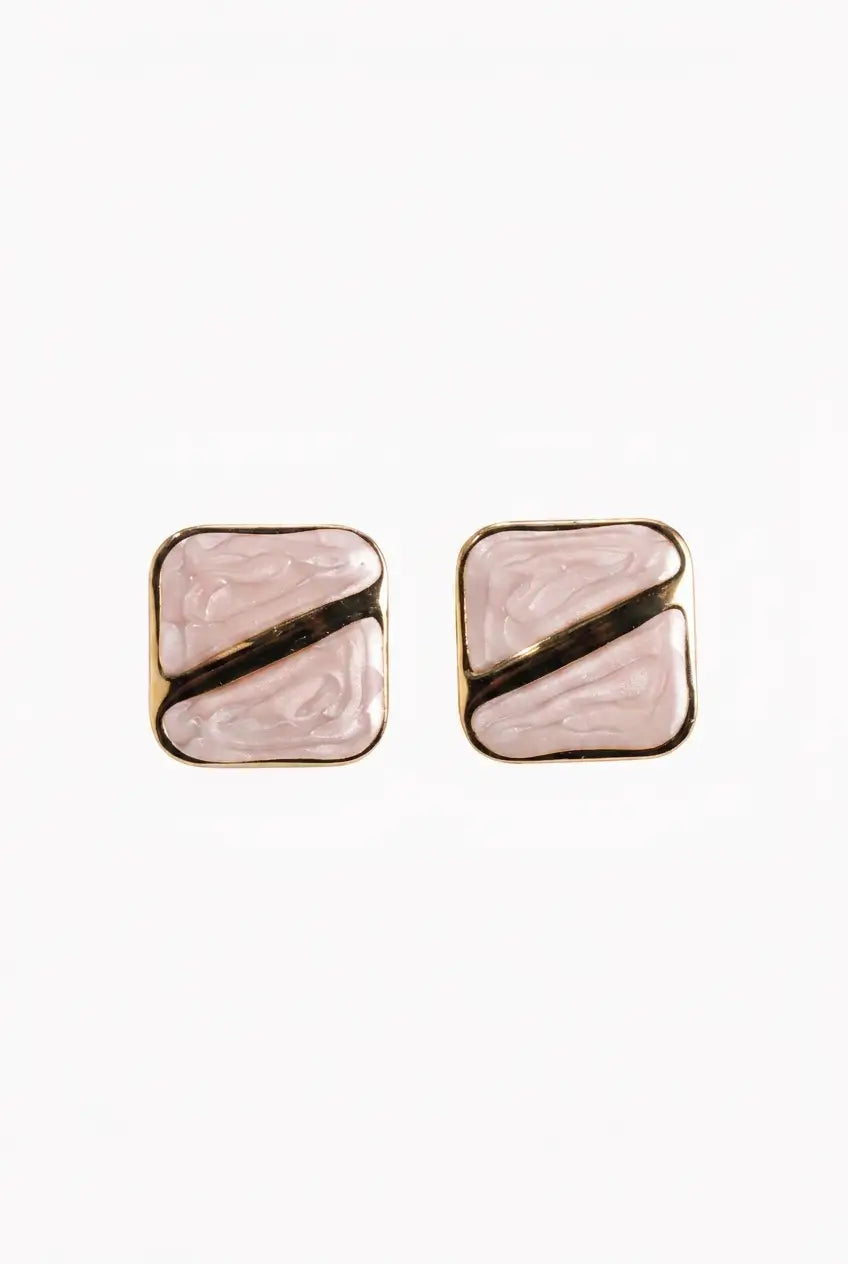 A pair of square stud earrings with a light pink marbled resin inlay, divided diagonally by a metallic gold band, set in a gold-tone frame.