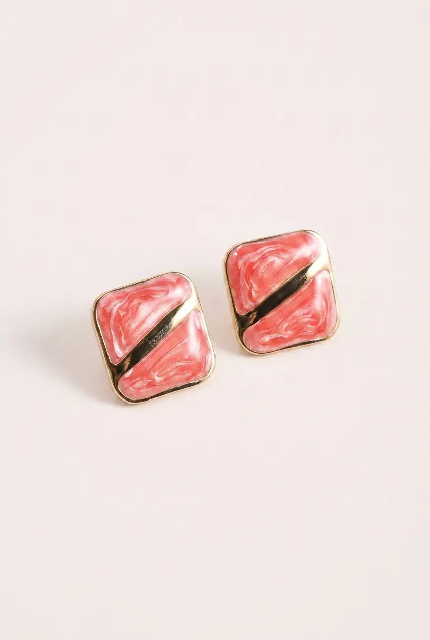 A pair of square stud earrings with a pink and white marbled enamel design, divided diagonally by a thin gold line, set in a gold-tone metal frame.