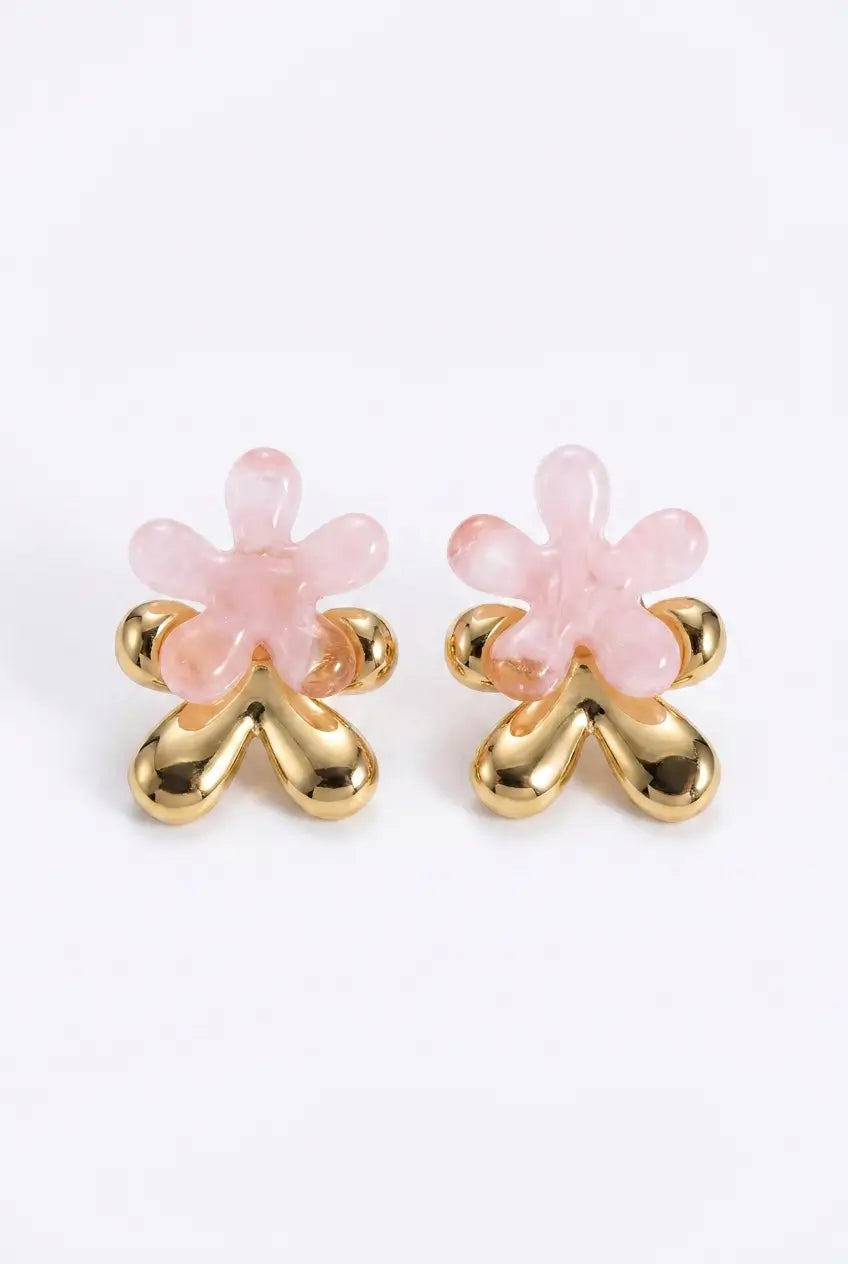 A pair of gold and pink stud earrings shaped like stylized flowers, photographed on a clean white background.